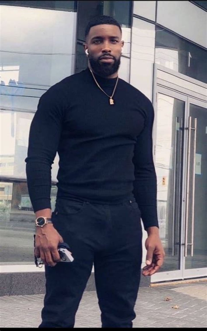 a man wearing a black t shirt looking off into the distance with his